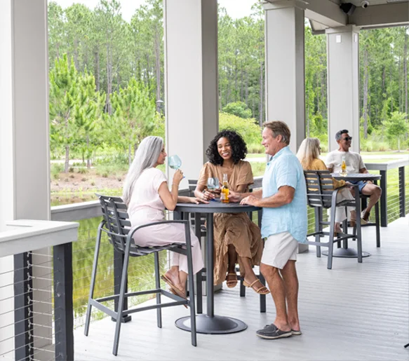 Neighbors gathered at high-top tables on the covered patio at the Community Lookout at Tributary.