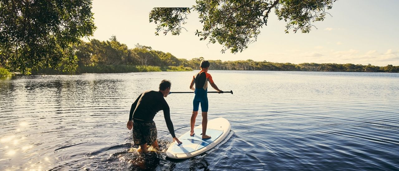Father son paddle boarding on river