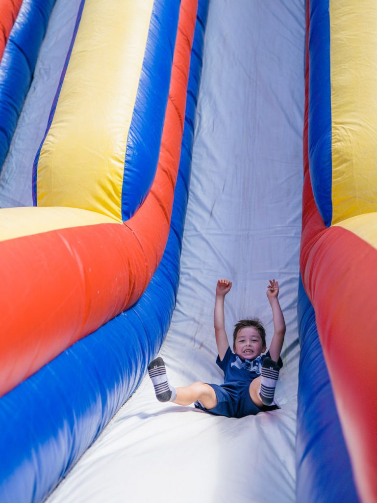 kid smiling down a slide at Tributary Model Home Event