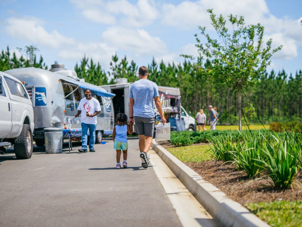 father and daughter walking to food trucks at Tributary Model Home Event