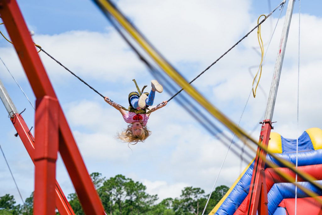 little girl upside down on sling shot at Tributary Model Home Event