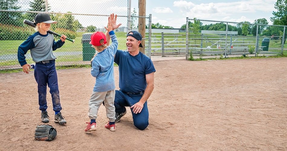 dad and son high-fiving on the baseball field