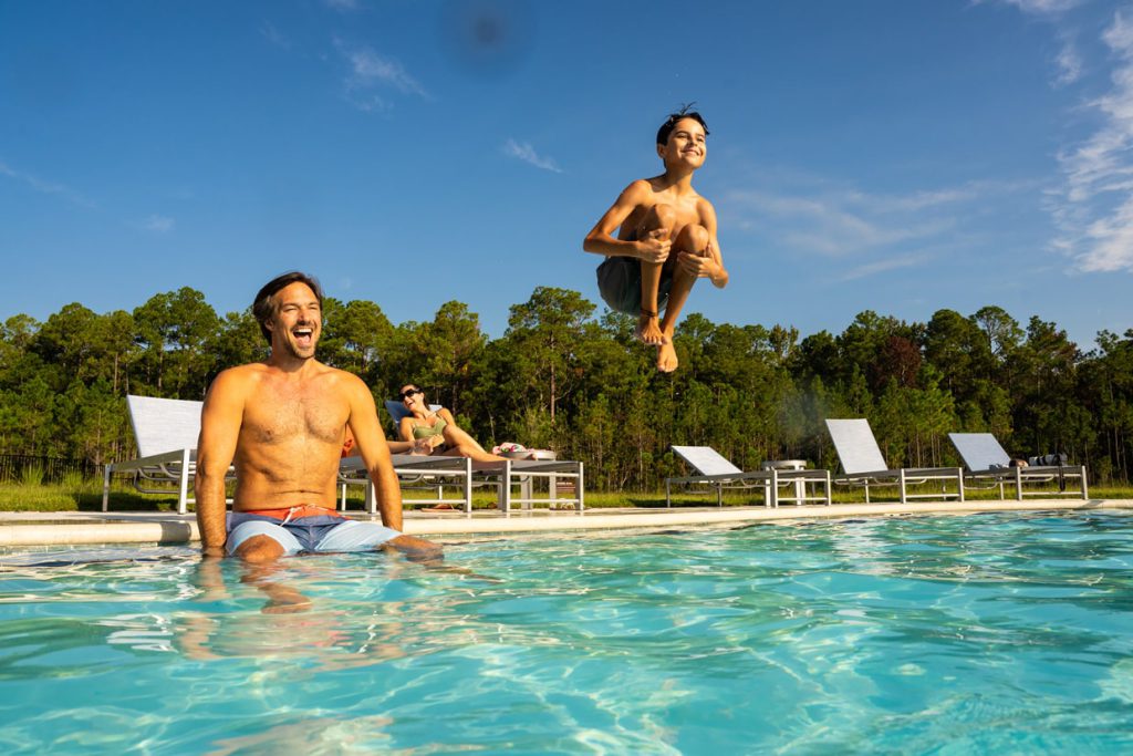 boy doing a canon ball into the pool at tributary