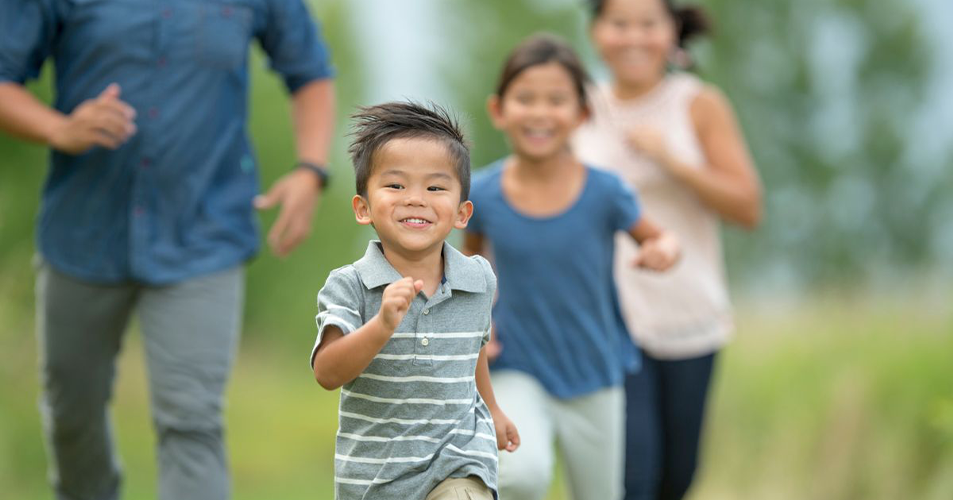Smiling child running ahead of family on grassy field