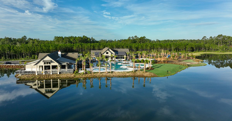 Aerial view of clubhouse and pool beside calm lake