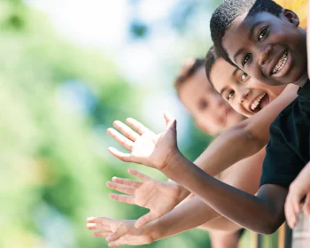 Smiling children waving from the windows of a yellow school bus