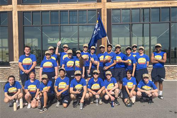 Group of high school students in matching blue shirts posing outdoors